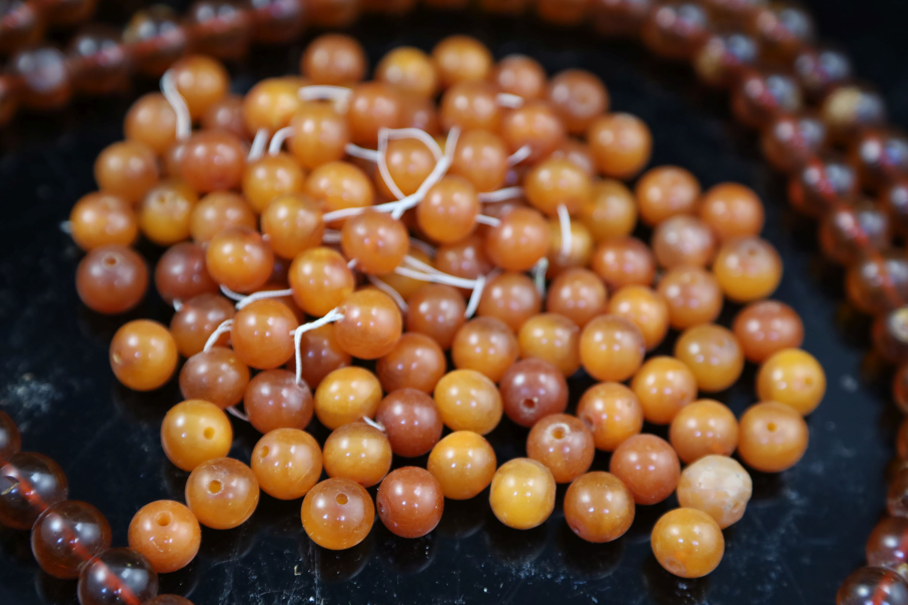 A single strand translucent amber bead necklace, 132cm, gross 153 grams and one other amber necklace (now loose), gross 126 grams.
